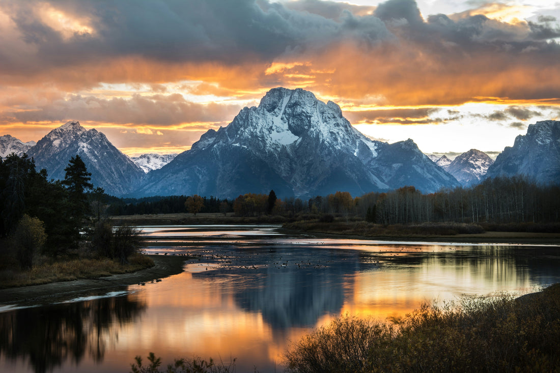 A dramatic sunset over Oxbow Bend in Grand Teton National Park, with Mount Moran reflecting in the calm waters