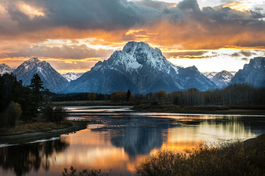 A dramatic sunset over Oxbow Bend in Grand Teton National Park, with Mount Moran reflecting in the calm waters